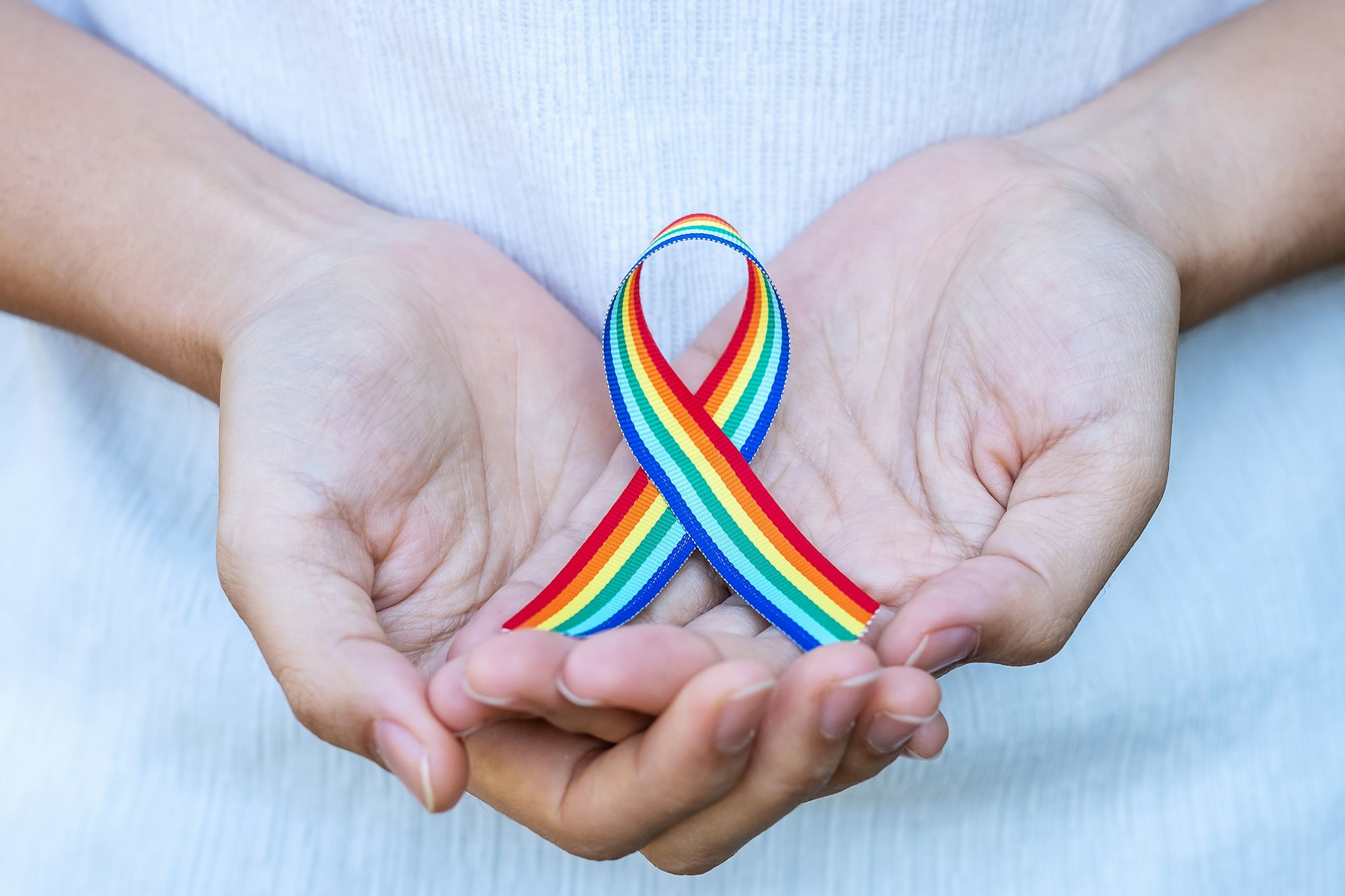 hand showing LGBTQ Rainbow ribbon